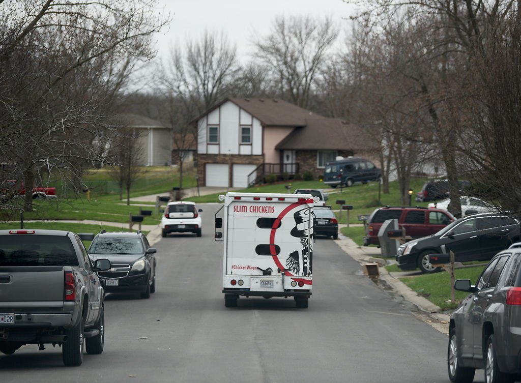 A Slim Chickens food truck drives through a neighborhood